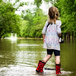Kind mit Gummistiefeln in Hochwasser